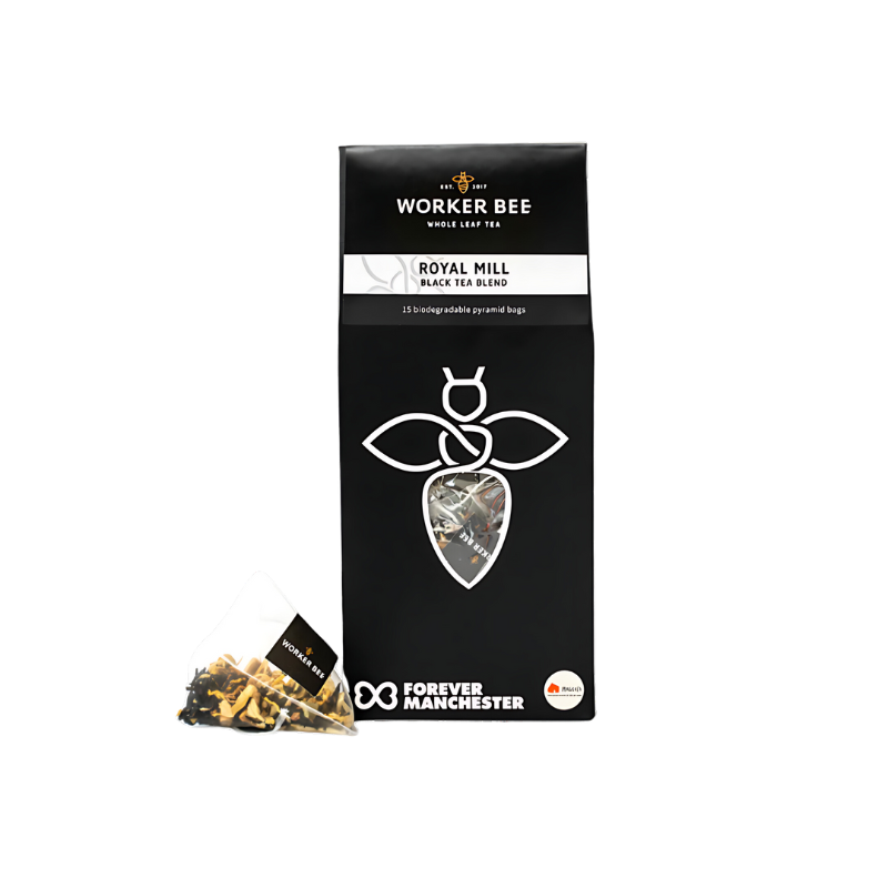 A black pack of Worker Bee Tea & Coffee Royal Mill Whole Leaf Tea Sacks (15) with a bee logo is shown. A pyramid tea bag displaying loose tea is in front. The Forever Manchester logo appears on the packaging.