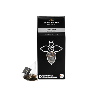 A black box of Worker Bee Tea & Coffee Earl Grey Whole Leaf Tea Sacks (15), made with Sri Lankan black tea and bergamot, displays a white bee logo. A single tea sack is placed in front; Forever Manchester logo appears at the bottom.