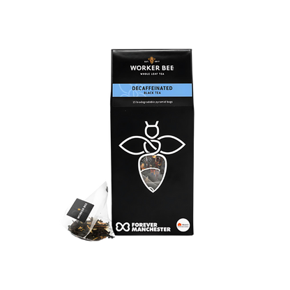 A black box of Worker Bee Tea & Coffee Decaffeinated Tea Sacks (15), made with premium Sri Lankan tea, featuring a white bee logo, a visible pyramid tea bag, and the Forever Manchester logo at the bottom.