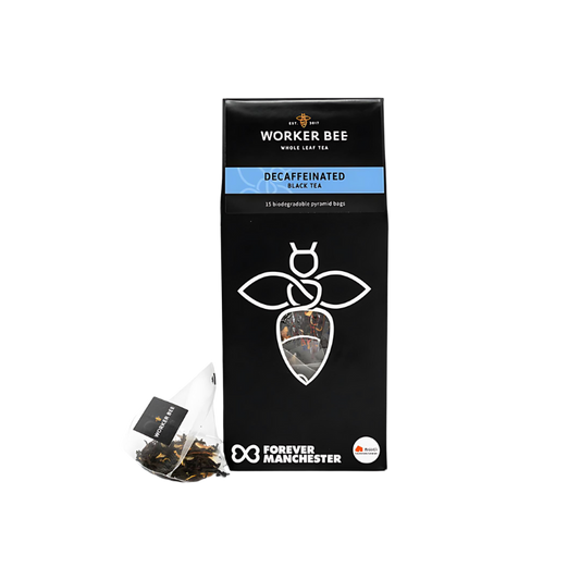 A black box of Worker Bee Tea & Coffee Decaffeinated Tea Sacks (15), made with premium Sri Lankan tea, featuring a white bee logo, a visible pyramid tea bag, and the Forever Manchester logo at the bottom.