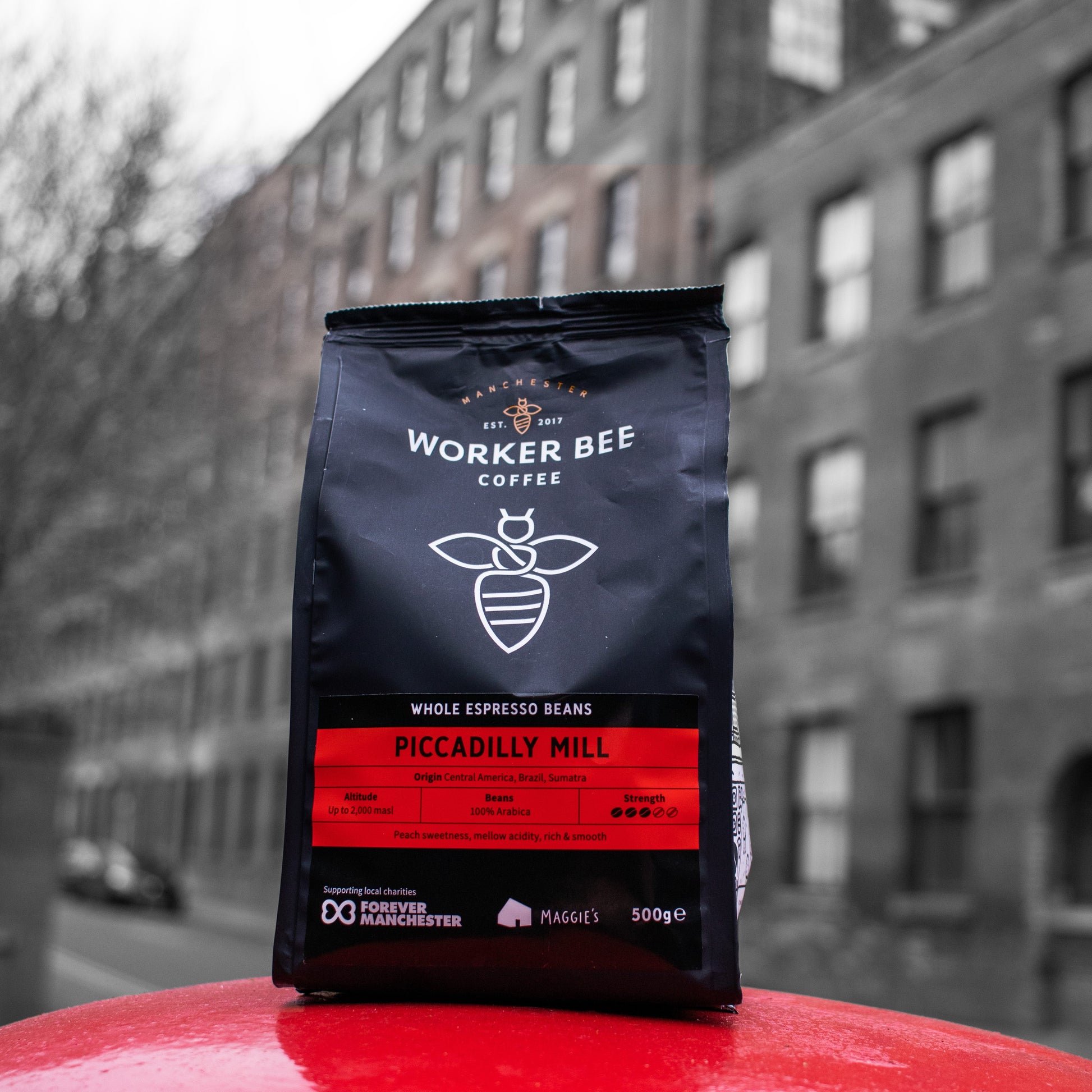 Worker Bee Coffee bag on a red surface with a blurred building in the background