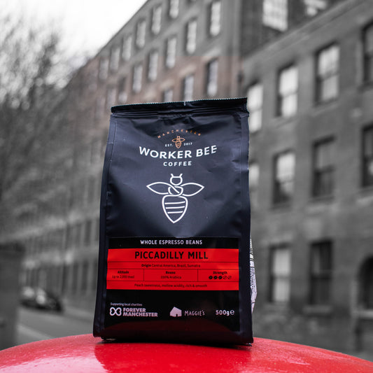 Worker Bee Coffee bag on a red surface with a blurred building in the background